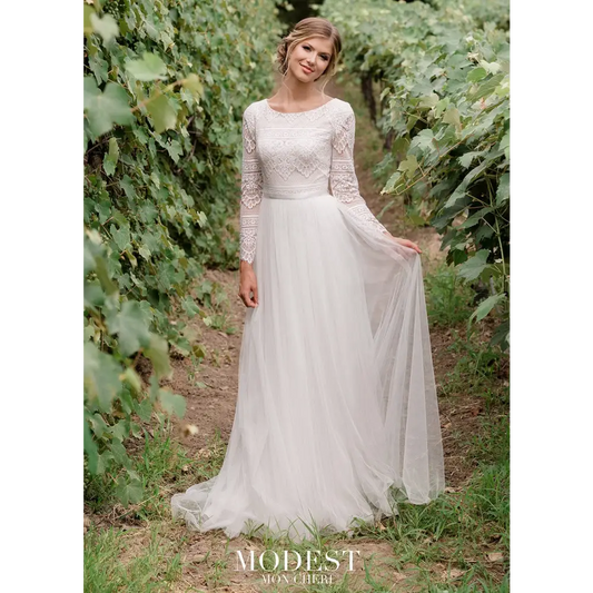 This boho chic allover lace and tulle A-line gown features a gorgeous lace bodice with scalloped long sleeves, a Sabrina neckline, a satin ribbon belt at the natural waist, and covered buttons along the back zipper that cascade down onto the gathered tulle skirt and sweep train. #utahbridalshop #weddingdresses #weddingaccessories #bridalcloset #classyweddings #brides #utahweddings #designerweddinggowns #modestgowns #trendyweddingdresses #uniqueweddinggowns