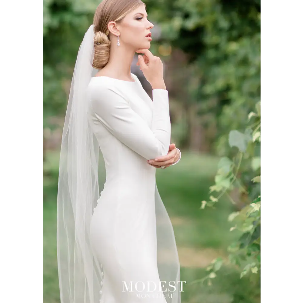 Your own royal moment in this simple and elegant stretch jersey trumpet gown featuring long sleeves, a bateau neckline, a dropped waist, princess seams, a zipper back with covered buttons down to the hem and a chapel train.#utahbridalshop #weddingdresses #weddingaccessories #bridalcloset #classyweddings #brides #utahweddings #designerweddinggowns #modestgowns #trendyweddingdresses #uniqueweddinggowns
