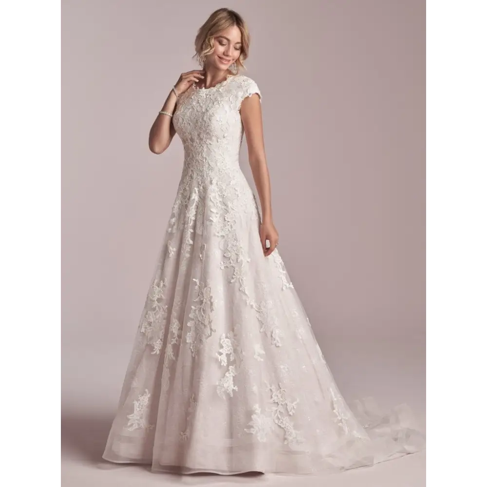 This modest cap-sleeved lace A-line wedding dress is classic, flattering, and fit for a princess. Additional coverage to our Courtney gown Sequined lace motifs over tulle and Lined lace cap-sleeves Lined with Virtue stretch jersey for comfort Pearl button over zipper closure Double horsehair hem finish Available in plus size. #utahbridalshop #weddingdresses #weddingaccessories #bridalcloset #classyweddings #brides #utahweddings #designerweddinggowns #modestgowns #trendyweddingdresses #uniqueweddinggowns