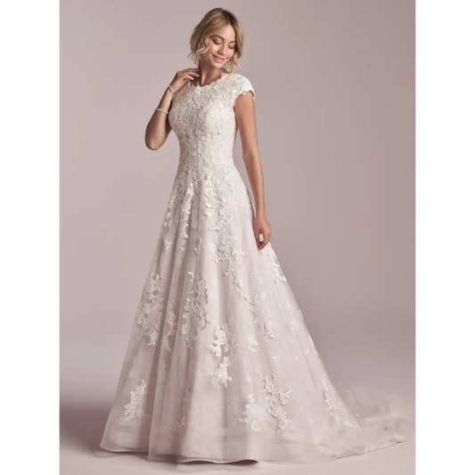 This modest cap-sleeved lace A-line wedding dress is classic, flattering, and fit for a princess. Additional coverage to our Courtney gown Sequined lace motifs over tulle and Lined lace cap-sleeves Lined with Virtue stretch jersey for comfort Pearl button over zipper closure Double horsehair hem finish Available in plus size. #utahbridalshop #weddingdresses #weddingaccessories #bridalcloset #classyweddings #brides #utahweddings #designerweddinggowns #modestgowns #trendyweddingdresses #uniqueweddinggowns